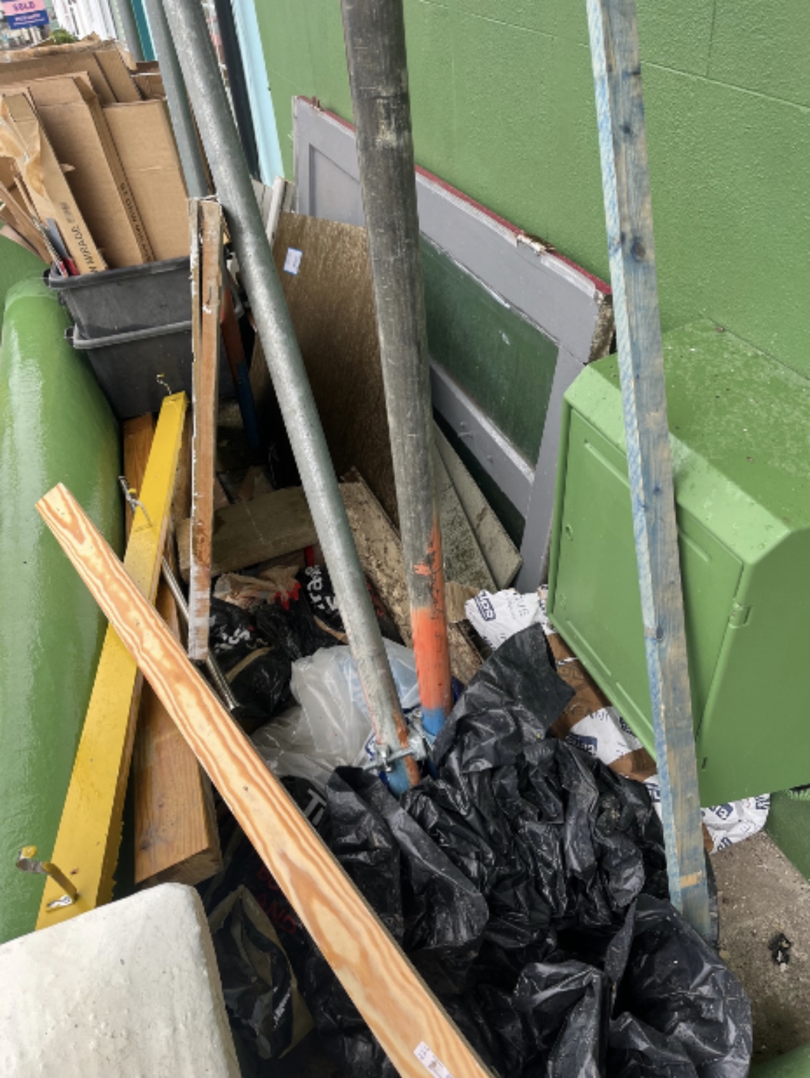 Scaffolding poles, timber and black rubble sacks piled alongside a building.